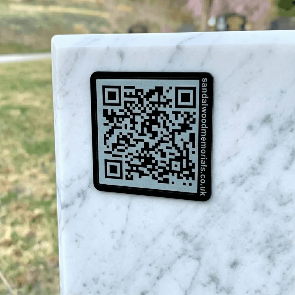 Black QR plaque with light code on a dark granite headstone