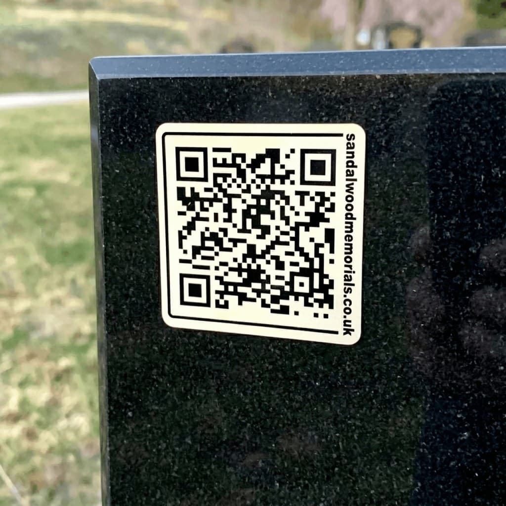 White QR plaque with dark code on a light marble headstone